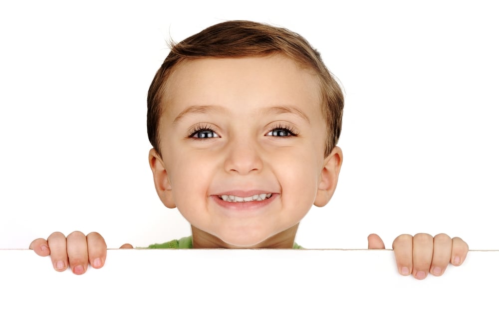 Cute kid smiling and holding a banner on white with copy space