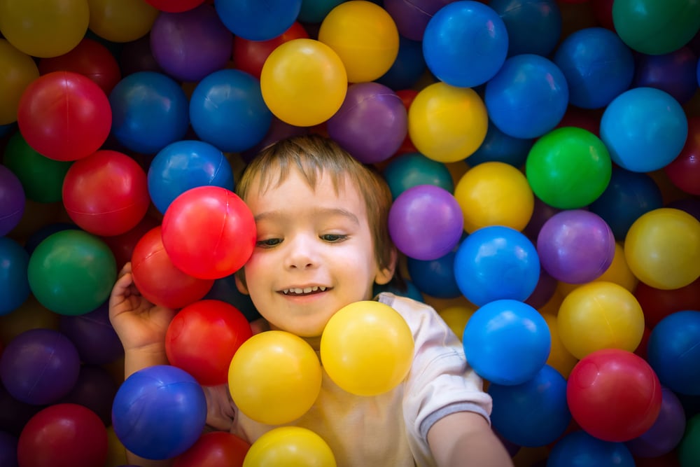 Happy cute child playing and having fun at kindergarten with colorful balls