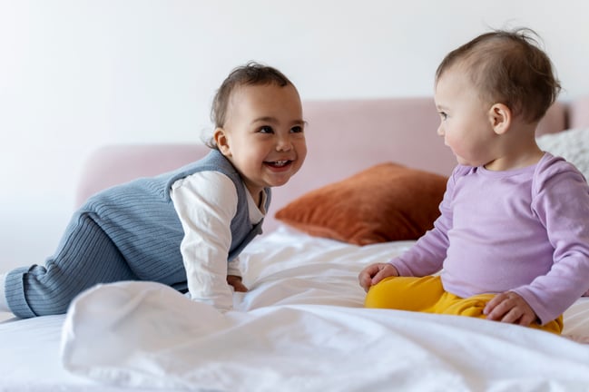 cute-babies-playing-with-each-other-bed-smiling