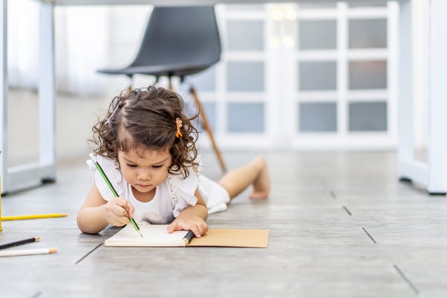 cute-little-girl-writing-notebook-lying-floor