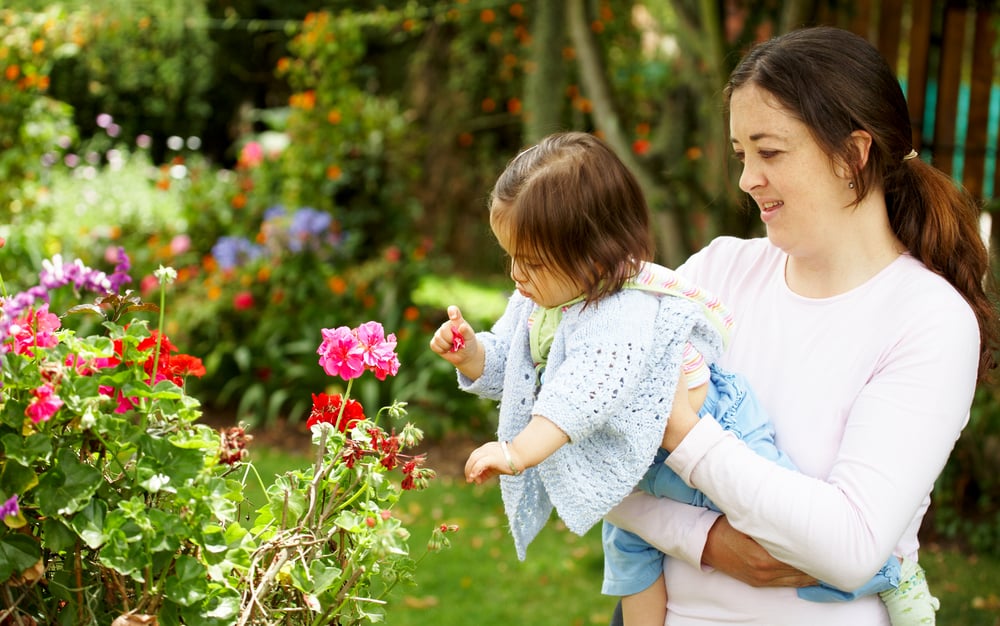 mother and daughter outdoors looking at some flowers